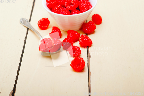 Image of bunch of fresh raspberry on a bowl and white table