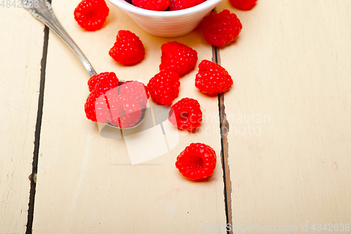 Image of bunch of fresh raspberry on a bowl and white table