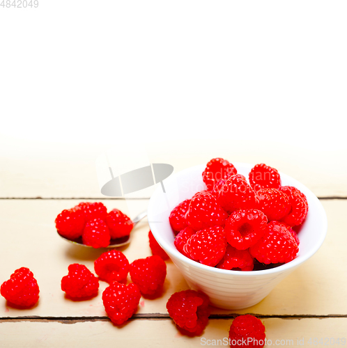 Image of bunch of fresh raspberry on a bowl and white table