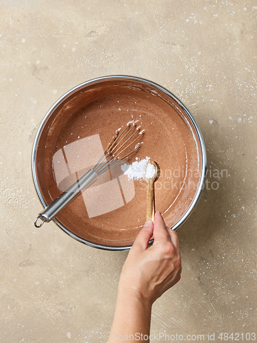 Image of adding baking soda in a chocolate cake dough