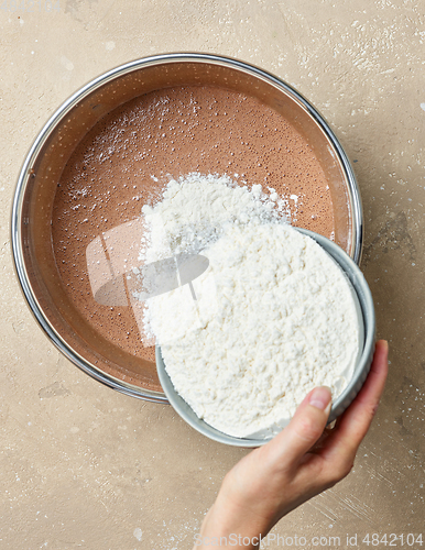 Image of add flour to the bowl of chocolate cake dough