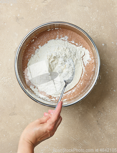 Image of add flour to the bowl of chocolate cake dough