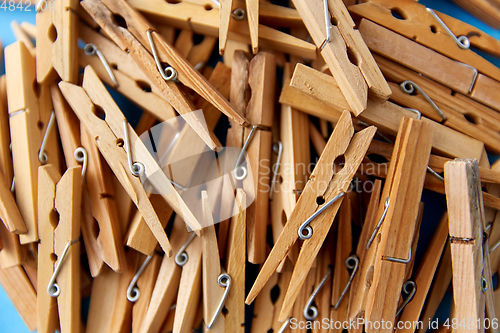 Image of close up of wooden clothespins on blue background