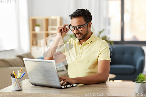 Image of indian man with laptop working at home office