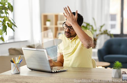 Image of stressed man with laptop working at home office