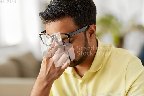 Image of tired man rubbing his nose bridge at home