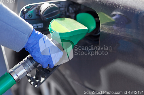 Image of close up of hand in glove filling car with petrol