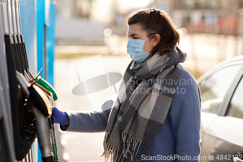 Image of young woman wearing medical mask at gas station