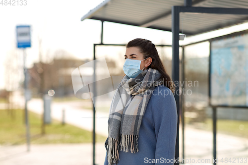 Image of young woman wearing medical mask at bus stop