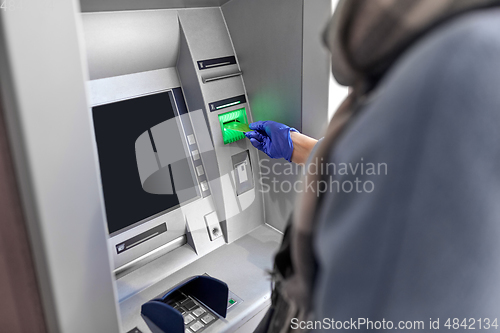 Image of woman in medical glove with credit card at atm