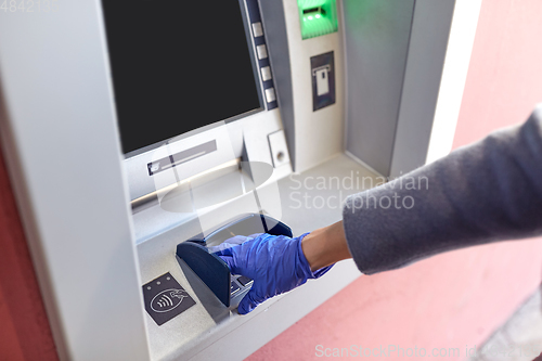Image of hand in medical glove entreing code at atm machine