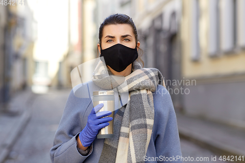 Image of woman in reusable mask with tumbler in city