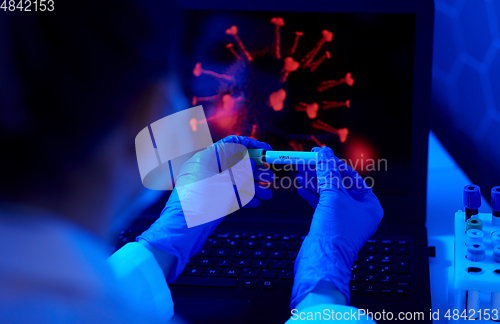 Image of hand holding beaker with coronavirus blood test