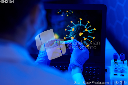 Image of hand holding beaker with coronavirus blood test