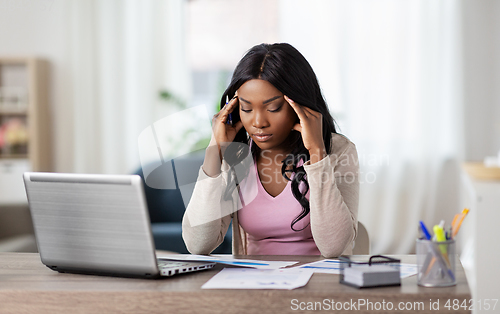 Image of stressed woman with papers working at home office
