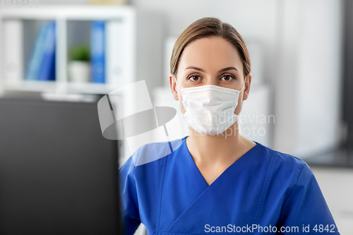 Image of doctor or nurse in mask with computer at hospital