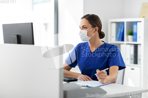 Image of doctor or nurse in mask with clipboard at hospital