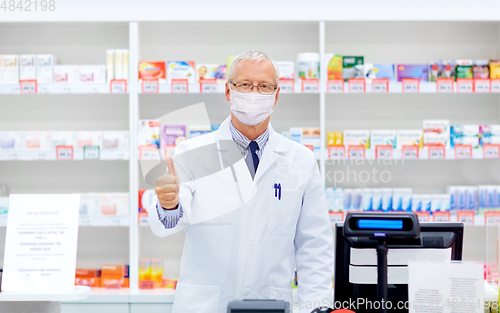 Image of old apothecary in mask at pharmacy shows thumbs up