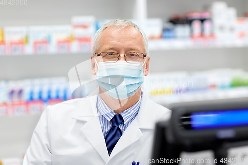 Image of senior apothecary in mask at pharmacy