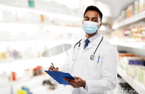 Image of indian doctor in mask with clipboard at pharmacy