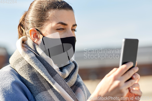 Image of woman in face mask with smartphone in city