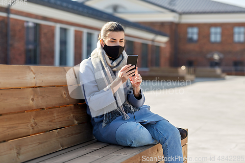 Image of woman in face mask with smartphone in city