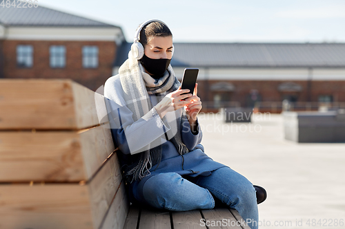 Image of woman in face mask with smartphone in city