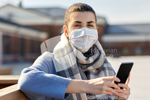 Image of woman in face mask with smartphone in city