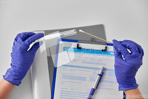 Image of hands in gloves holding test tube and cotton swab