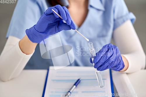 Image of hands in gloves holding test tube and cotton swab