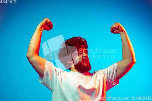 Image of Caucasian man\'s portrait isolated on blue studio background in neon light