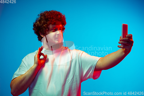 Image of Caucasian man\'s portrait isolated on blue studio background in neon light