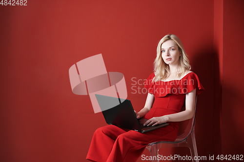 Image of Young adult woman sitting on a chair and working on laptop