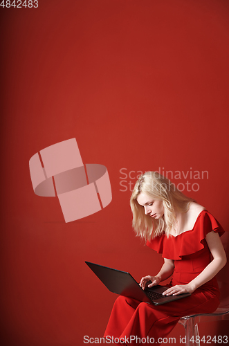 Image of Young adult woman sitting on a chair and working on laptop