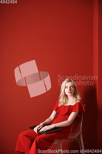 Image of Young adult woman sitting on a chair and holding laptop