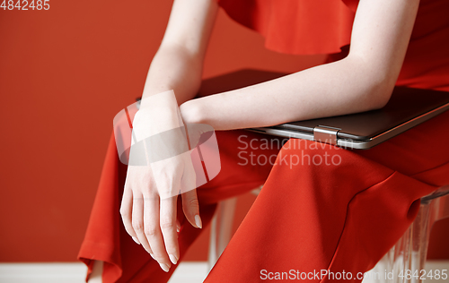 Image of Young adult woman sitting on a chair and holding laptop