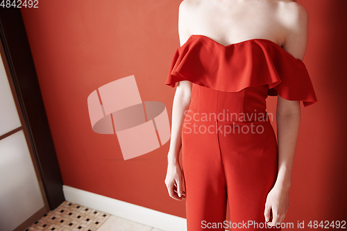 Image of Young adult woman wearing red jumpsuit and standing next to the