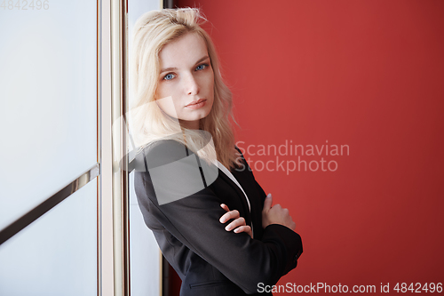 Image of Young adult business woman standing next to the window