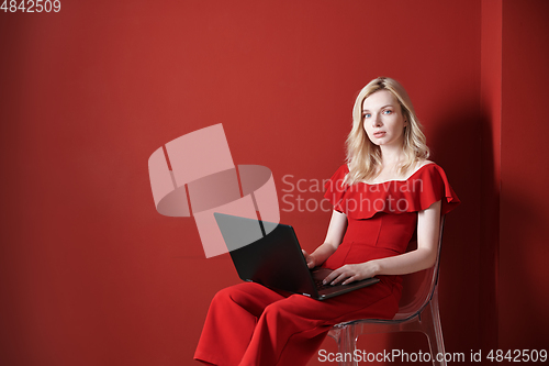 Image of Young adult woman sitting on a chair and working on laptop