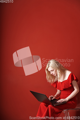 Image of Young adult woman sitting on a chair and working on laptop