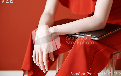 Image of Young adult woman sitting on a chair and holding laptop