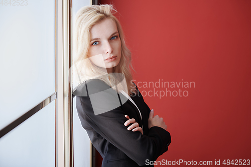 Image of Young adult business woman standing next to the window