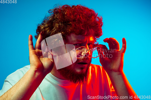 Image of Caucasian man\'s portrait isolated on blue studio background in neon light