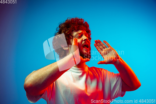 Image of Caucasian man\'s portrait isolated on blue studio background in neon light