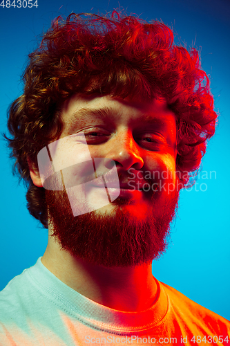 Image of Caucasian close up man\'s portrait isolated on blue studio background in neon light