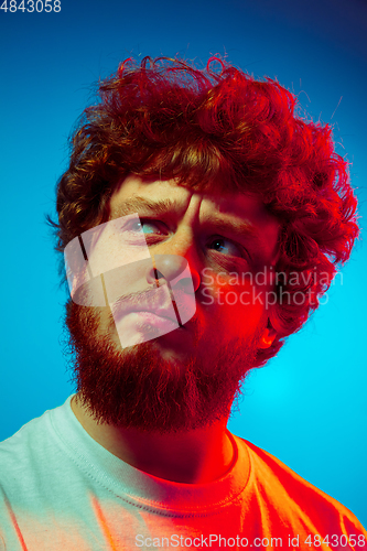 Image of Caucasian close up man\'s portrait isolated on blue studio background in neon light