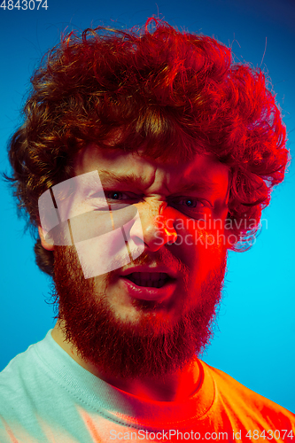 Image of Caucasian close up man\'s portrait isolated on blue studio background in neon light