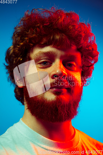 Image of Caucasian close up man\'s portrait isolated on blue studio background in neon light