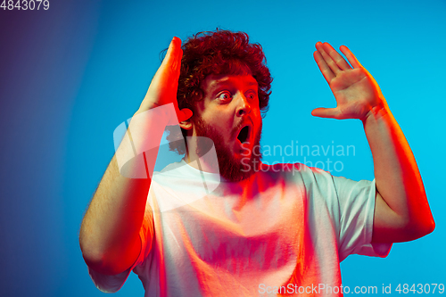 Image of Caucasian man\'s portrait isolated on blue studio background in neon light