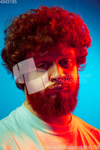 Image of Caucasian close up man\'s portrait isolated on blue studio background in neon light